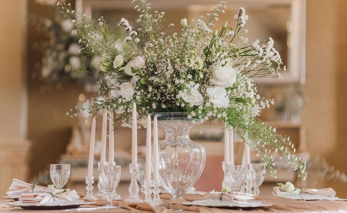 Blumendeko runde Tische mit üppigem Schleierkraut, weißen Blumen, Glasvasen und eleganter Hochzeits-Tischdekoration