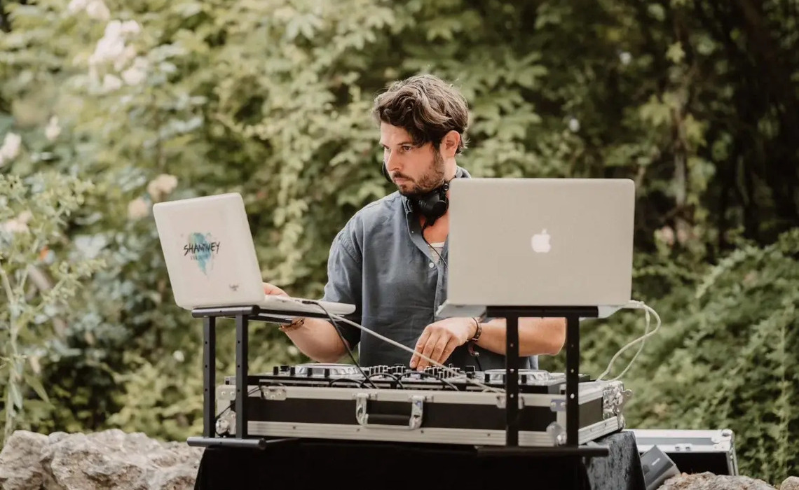 Professioneller Hochzeits-DJ arbeitet mit DJ-Controller und Laptop bei einer Hochzeit als Beispiel für Erfahrung und Technik