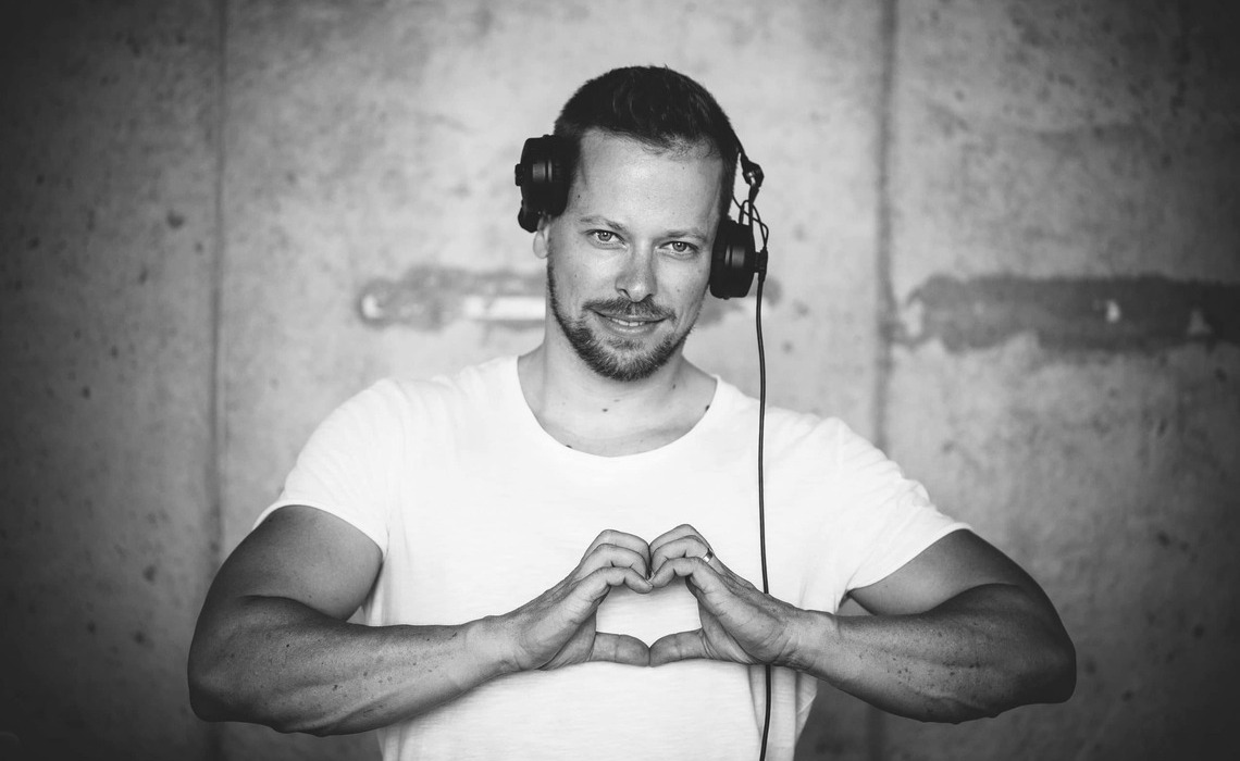 Professioneller Hochzeits-DJ mit Kopfhörern formt ein Herz mit den Händen als Symbol für Erfahrung, Leidenschaft und Qualität