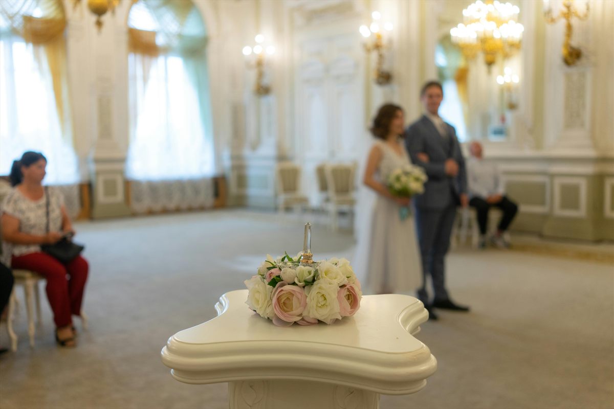 Trauzimmer mit Brautpaar im Hintergrund und Blumen auf einem weißen Tisch